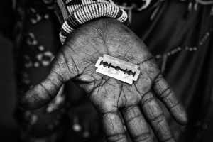 Mother of Isina is showing the tool which will be used for the circumcision.